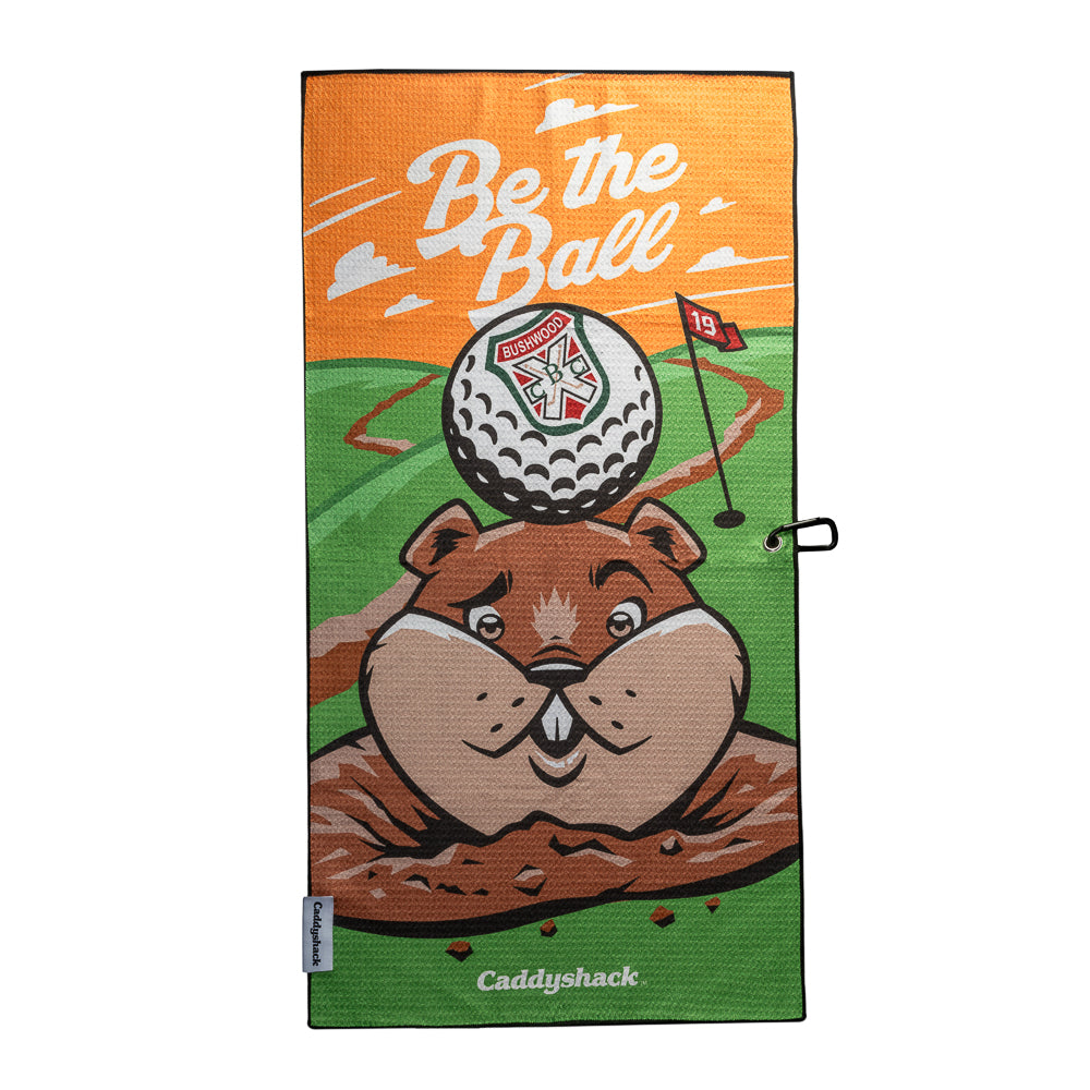 Caddyshack golf towel with white “Be the Ball” lettering, orange sky, green course, red 19 flag, and gopher balancing a Bushwood crest golf ball on its head.